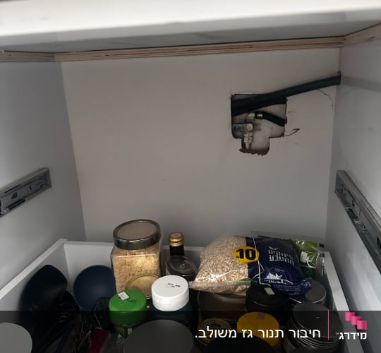 צינור גז חשוף בארון מטבח עם מוצרי מזון